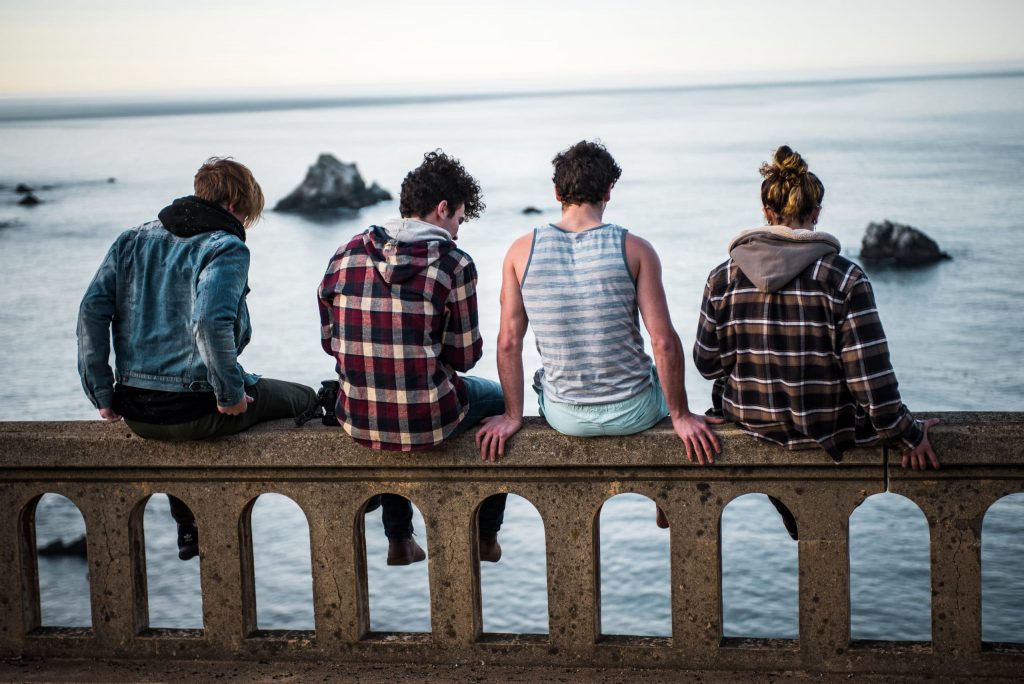 young adults sitting on a concrete fence