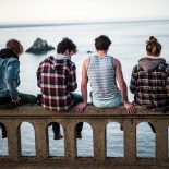 young adults sitting on a concrete fence